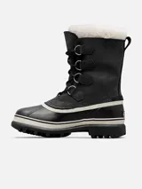 Botas de nieve Sorel modelo Caribou para mujer, de color negro con base de goma vulcanizada impermeable y detalles en blanco. Cuentan con parte superior de gamuza y nylon, cordones frontales con anillas metálicas y borde superior de pelo sintético blanco.