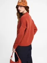 Sweater de tejido de punto color ladrillo. Escote en v y mangas largas de sisa caída. Confeccionado en lana.