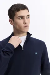 Buzo de punto con medio cierre frontal, cuello elevado y puños acanalados. Presenta un pequeño logo bordado en el pecho.