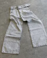 Pantalón de jean gris claro, corte wide leg, con cinturón de la misma tela.