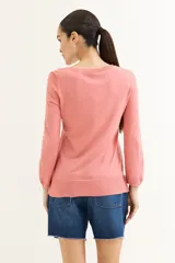 Sweater rosado de tejido de punto con escote en V y mangas largas con puños acanalados. El ruedo también es acanalado y presenta un detalle de crochet.
