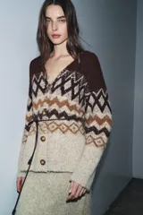 Chaqueta de punto con escote en pico y manga larga, confeccionada en tejido jacquard con diseño geométrico. Presenta detalles de lentejuelas y abalorios, cierre frontal con botones y un cinturón fino ajustable en la cintura.