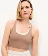 Top deportivo de microfibra marca Get Over, de diseño bicolor en tonos marrón y marfil, con escote redondo, capas superpuestas, breteles anchos cruzados y abertura en la espalda.