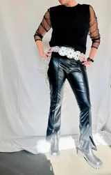 Pantalón negro de eco cuero con corte ajustado, tiro alto y abertura en el bajo.