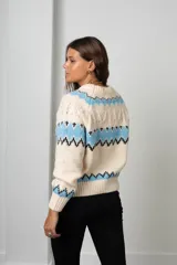 Buzo de tejido de punto con diseño nórdico, cuello redondo acanalado y mangas largas. Presenta un patrón geométrico en tonos celeste, negro y crema.