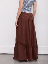 Falda larga color marrón, de corte amplio y fluido, con cintura elástica fruncida, bolsillos laterales y detalle de volado horizontal en la parte inferior.