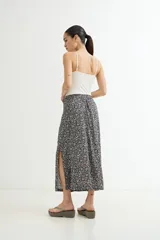 Falda midi cruzada (wrap) de viscosa, color azul marino con estampado floral pequeño en blanco. Presenta un tajo lateral pronunciado.