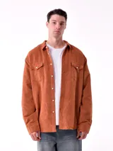 Sobrecamisa de hombre color terracota, confeccionada en pana de algodón, con cuello camisero, botones frontales blancos y dos bolsillos de parche con solapa en el pecho.