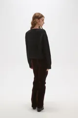 Sweater negro de punto con escote en V profundo y detalle de encaje en el borde del cuello. Presenta mangas largas con puños acanalados y un corte holgado.