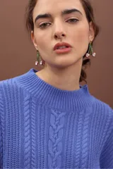 Sweater de punto negro con diseño de trenzas verticales, cuello alto y corte holgado de estilo oversize.