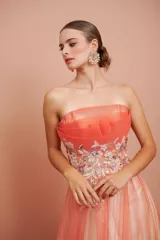 Vestido largo strapless de tul en degradé con tono coral y crema, con telas superpuestas y detalles bordados en el talle.