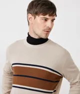 Suéter masculino de corte slim confeccionado en tejido de punto color beige. Presenta un diseño de rayas horizontales contrastantes en el pecho en tonos marrón y azul marino, cuello redondo, mangas largas y terminaciones en rib en puños y bajo.