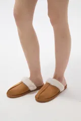 Pantuflas cerradas color marrón con ribetes de piel sintética en la abertura y suela plana.