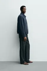 Cazadora boxy fit color azul marino, confeccionada en tejido de algodón. Presenta cuello solapa, manga larga con puño abotonado, bolsillos de vivo en la cadera y bajo elástico. Cierre frontal con cremallera.