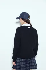 Sweater de punto color negro, con cuello redondo y diseño texturizado con ondas en relieve. Presenta mangas largas y un calce cómodo y holgado.