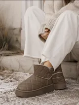 Bota corta tipo pantubota color beige, con diseño acolchado de costuras en forma de rombos, suela de plataforma plana y forro interior de piel sintética.