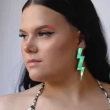 Par de aros colgantes con forma de rayo, con superficie holográfica que refleja tonos rosados, celestes y azules.