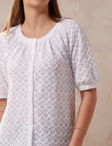 Blusa blanca de tejido calado, marca Sabrina Lauren. Cuello a la base y abertura central con botones.
