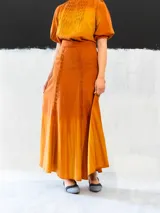 Falda larga color ocre con teñido degradado horizontal en tonos anaranjados. Confeccionada en algodón tipo seda, corte a la cintura, bolsillos laterales y cierre invisible.