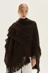 Ruana tejida en lana de cordero con diseño de sectores calados y terminación con flecos en los bordes.