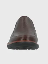 Zapato tipo mocasín Hush Puppies modelo Oregon, confeccionado en cuero vacuno con textura granulada. Presenta un diseño sin cordones con elásticos laterales para un ajuste cómodo, costuras reforzadas y suela de goma EVA de alto rendimiento.