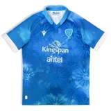 Camiseta de rugby celeste con detalles en blanco, con cuello en V y mangas cortas con puños blancos. Incluye logos de Macron, Kingspan y Antel, escudo de la Unión de Rugby del Uruguay y diseño con soles estilizados.