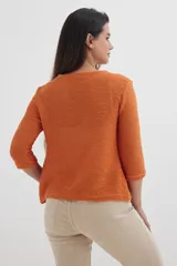 Cardigan verde esmeralda de tejido de punto calado, con mangas 3/4 y corte evasé. Presenta cuello redondo con abertura en forma de gota y cierre con un único botón.