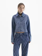 Camisa de denim azul de manga larga, corte cuadrado y silueta corta. Presenta un bordado integral en patrón de rombos con detalles en rosa y bordeaux.