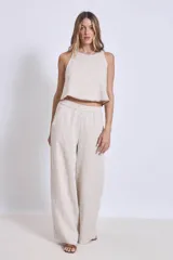 Pantalón de lino color beige, de corte amplio y tiro alto, con cintura elástica y bolsillos laterales.