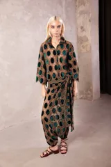 Camisa de corte oversize y manga 3/4, confeccionada en encaje con diseño de círculos de terciopelo en color verde sobre base marrón. Presenta cuello clásico y cierre frontal con botones transparentes.