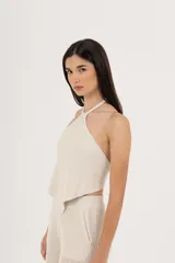 Top de tejido de punto color crema, con cuello halter y espalda descubierta.