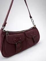 Cartera de hombro tipo baguette color bordó, confeccionada en material con textura gamuzada. Presenta dos bolsillos frontales con solapa y cierre de hebilla metálica, además de un compartimento principal con cierre. Incluye una correa fija con detalle de cadena metálica en uno de sus extremos.