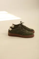 Zapatillas de gamuza en color verde oliva, con suela de goma color marrón y detalle de talón en contraste color crema.