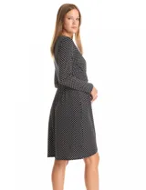 Vestido envolvente de seda fría estampado en blanco y negro, marca Luxology. Presenta escote en V cruzado, cintura elastizada con apliques metálicos en el lateral, manga larga entallada y ruedo asimétrico en el frente.