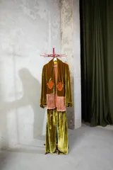 Camisa de seda en color verde petróleo, con corte recto y estructura clásica. Presenta un diseño con apliques bordados en tono borravino y detalles de flecos largos en la parte frontal inferior.