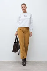 Blusa blanca de manga larga con cuello redondo, confeccionada en tela liviana con detalles de encaje vertical y bordado floral en el pecho.