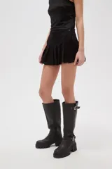 Falda mini tableada de tiro bajo, color negro, con cierre lateral y botón.