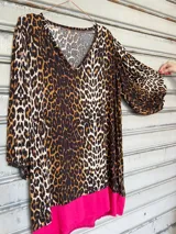Túnica de mangas 3/4 con estampado animal print y ruedo irregular con terminación en tela fucsia.