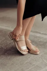 Sandalia Roma de cuero dorado, con tiras anchas, una lisa en la puntera y otra con textura reptil en el empeine, y tira ajustable al talón con hebilla. Suela plana y cómoda.