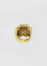 Anillo dorado con forma de trébol de cuatro hojas, con detalles texturizados en dos de las hojas.