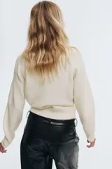 Buzo de punto suave con cuello tipo polo, mangas raglán y terminaciones acanaladas en puños y bajo.