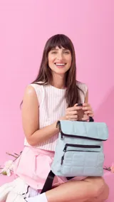 Mochila de nylon capitoneada color celeste, con diseño acolchado en cuadrícula. Posee un compartimento principal con cierre y solapa, además de dos bolsillos frontales con cierres negros a la vista.