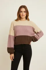 Sweater de tejido grueso con diseño de bloques de color horizontales: beige claro, rosado y marrón oscuro. Presenta cuello redondo y mangas largas abullonadas.