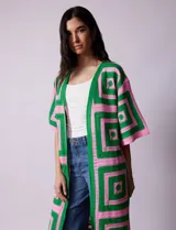 Cardigan largo tejido al crochet con diseño geométrico en verde y rosa. Tiene mangas 3/4 y corte holgado.