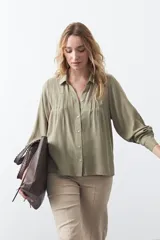 Camisa de manga larga en color celeste, con diseño de corte relajado, cuello clásico y detalle de tablas verticales en el frente.
