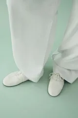 Zapatos planos de piel color blanco, con cierre de cordones en el empeine y detalle de pespuntes decorativos.