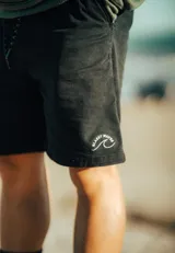 Bermuda negra de corte recto con cordón ajustable en la cintura y logo bordado en blanco en la pierna izquierda.