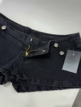 Short de denim negro de tiro bajo, con diseño de doble botonadura metálica decorativa en el frente.