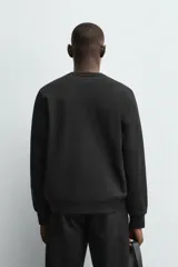 Sudadera de cuello redondo y manga larga, confeccionada en tejido de algodón pesado con interior de rizo ligeramente afelpado. Presenta un corte relajado y acabados en rib en puños y ruedo.