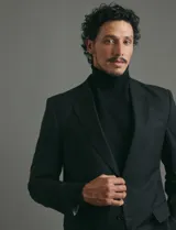 Traje de corte clásico compuesto por saco de dos botones y pantalón de vestir a juego. Diseño tradicional en color negro.